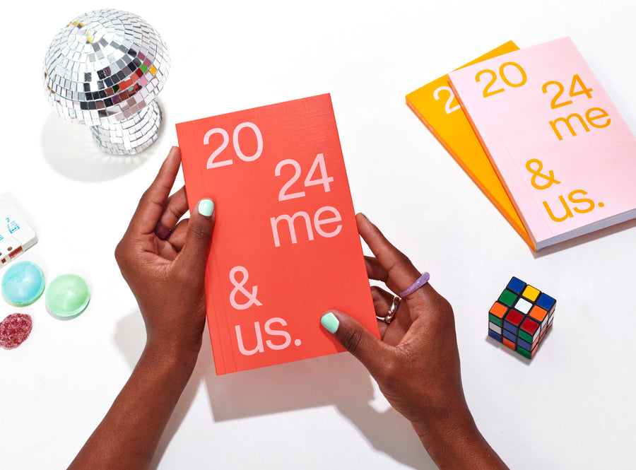 planner 2024 me & us, red cover hold in hands  by a black model, candies and other planners on the background
