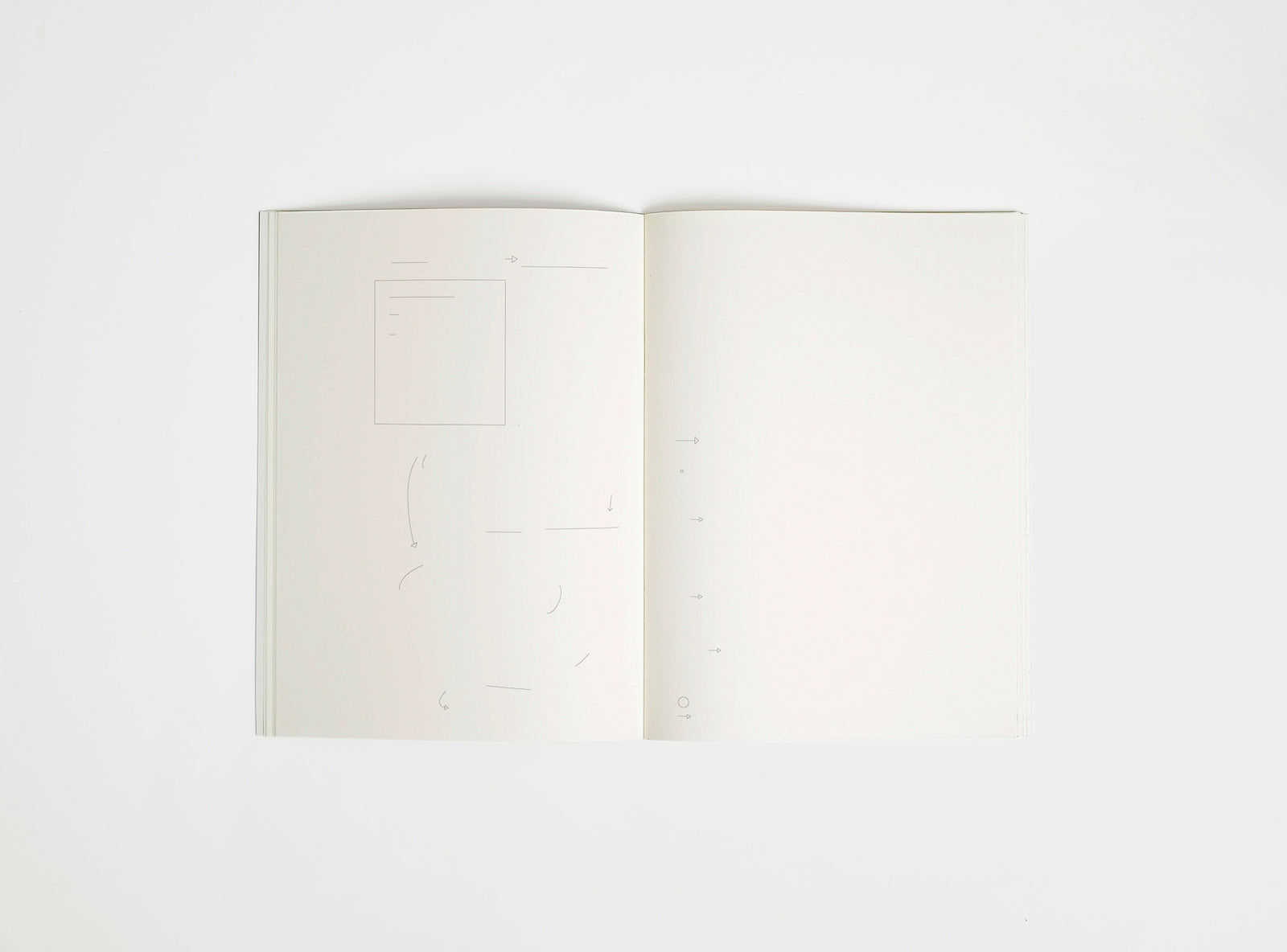 Open notebook edition julie joliat x studio playground with white pages on a white background, with scribbles printed on it.