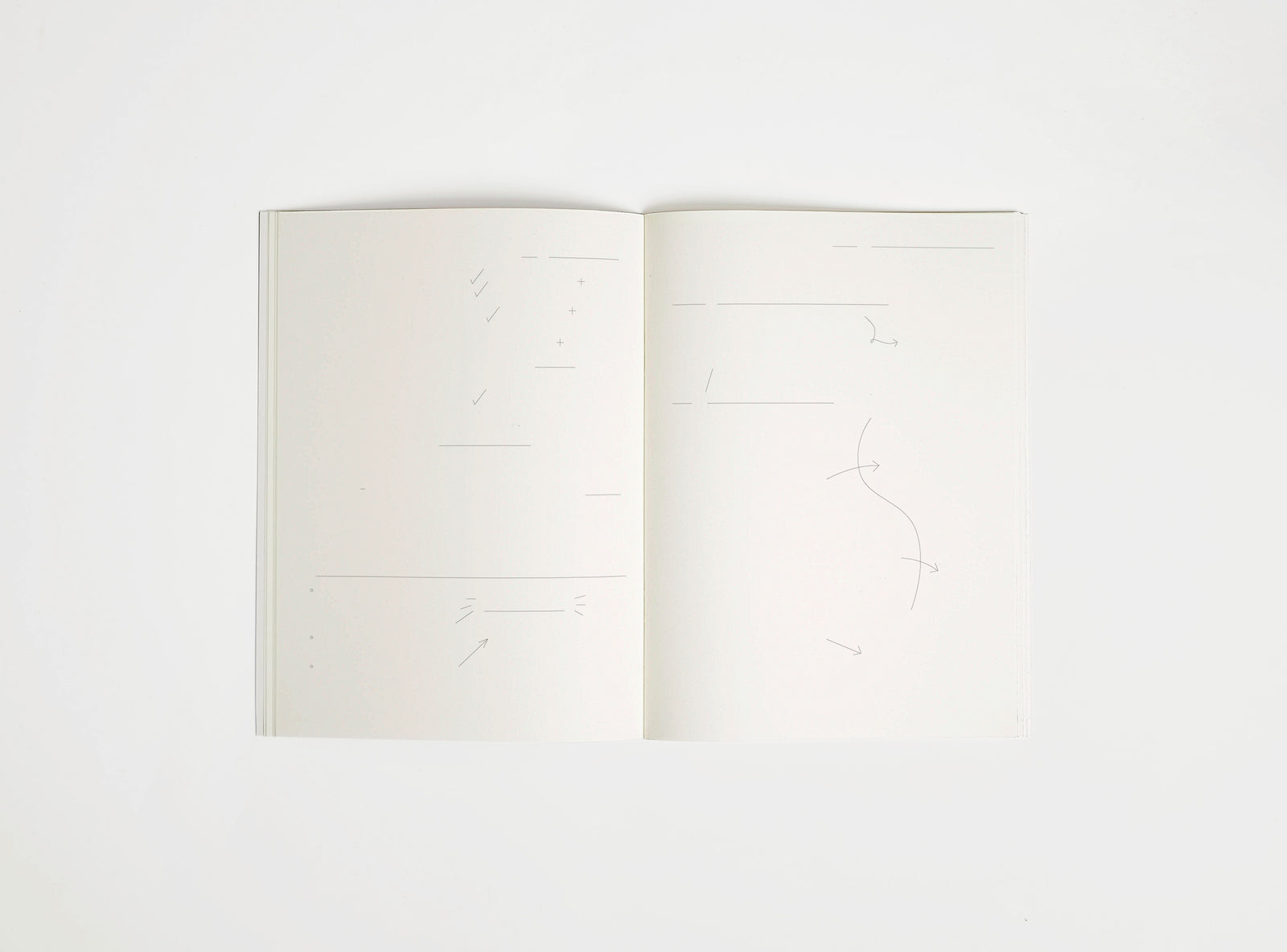 Open notebook edition julie joliat x studio playground with white pages on a white background, with scribbles printed on it.