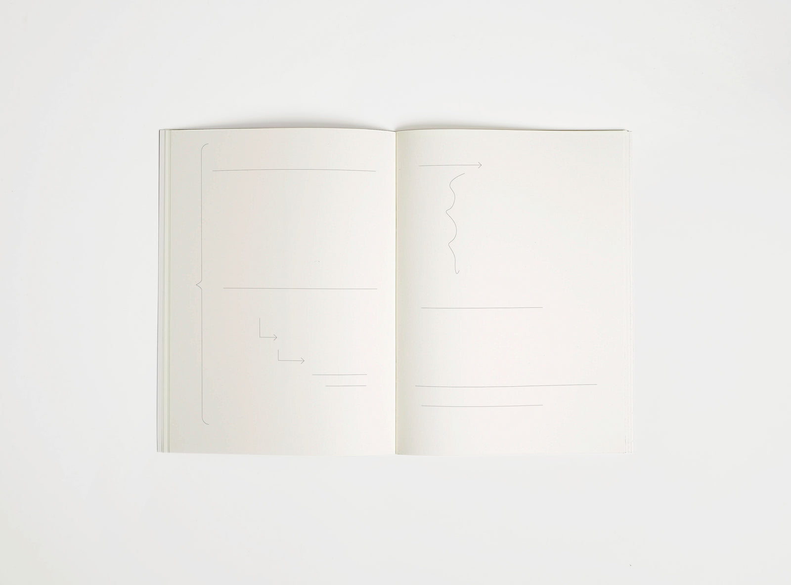 Open notebook edition julie joliat x studio playground with white pages on a white background, with scribbles printed on it.