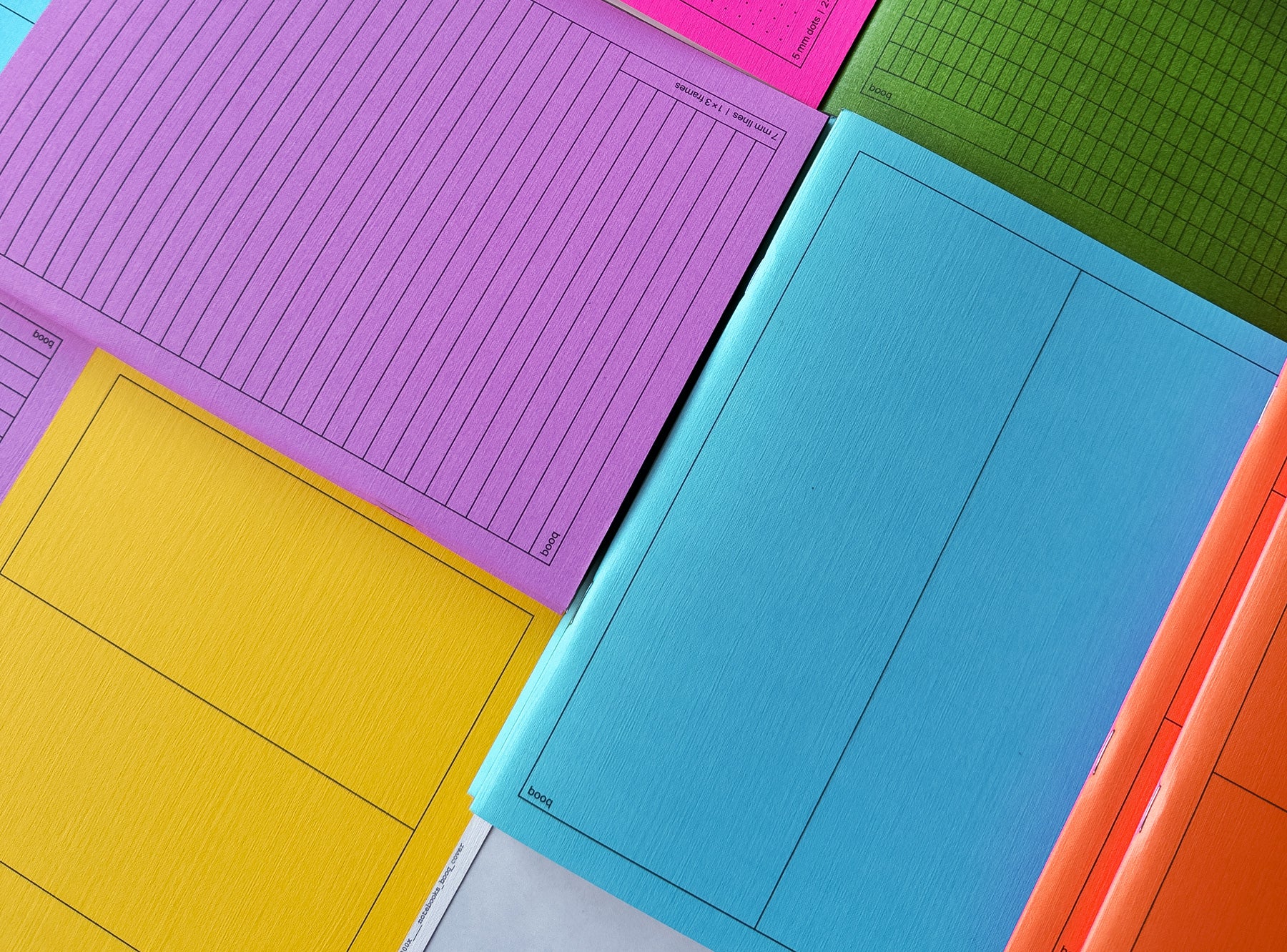 Colorful notebooks booq including pink, blue, green, yellow, and orange on a white background.
