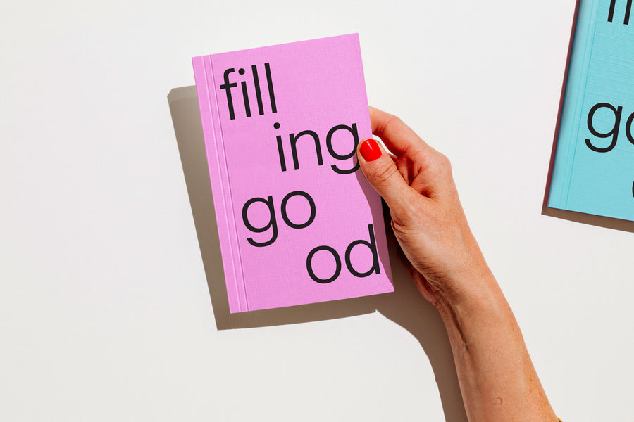 Hand holding a pink notebook with text on a light background