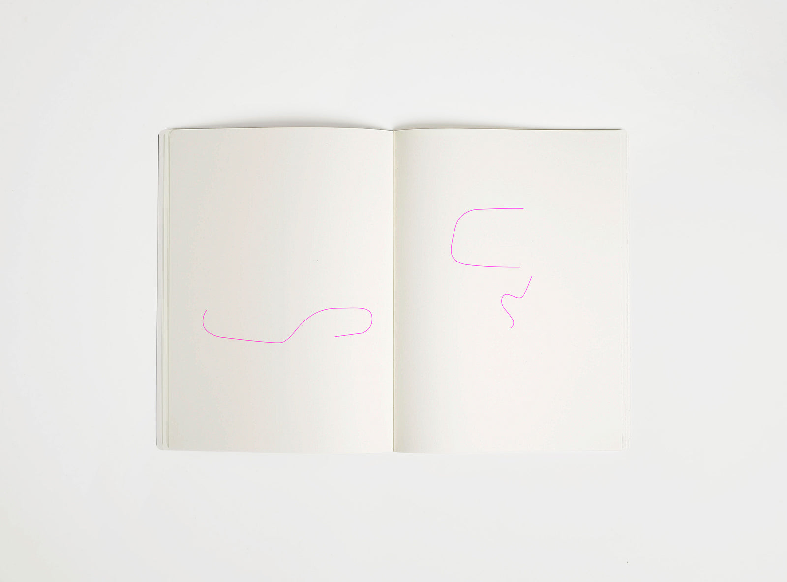 Open notebook with a pink drawing suggesting Eames Chair on white background, the iconic design piece
