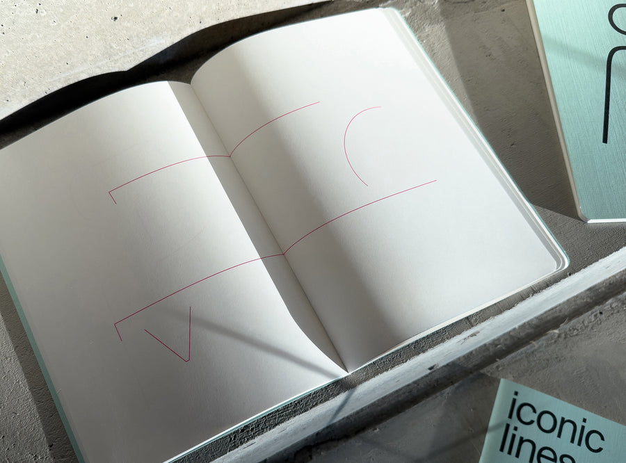 white notebook with pink outline drawing, open on beton stairs