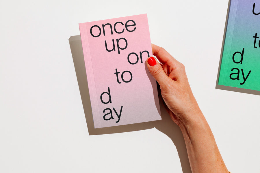 A hand with red nail polish holds a gradient planner 2027 that reads 'once upon today' in black lowercase text against a clean white background. edition julie joliat planner agenda 2027.