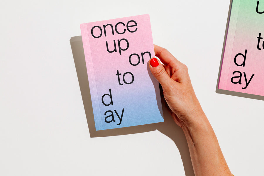 A hand with red nail polish holds a gradient planner 2027 that reads 'once upon today' in black lowercase text against a clean white background. edition julie joliat planner agenda 2027.
